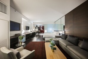 Una habitación de hotel moderna con sala de estar, comedor independiente, cama grande y televisor.