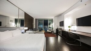 A modern hotel room with a large bed, a desk, a chair, a TV, and a balcony with a city view. - SVS: Sunset View Studio | Open Balcony | Resort Amenities | Palms Place (Las Vegas)