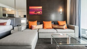 A modern hotel room with a sofa set, a glass coffee table, and a painting of a sunset. - Strip View Studio • Balcony • No Resort Fee • Free Parking • TE25 (Las Vegas)