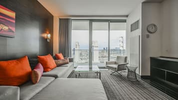 Una habitación de hotel moderna con un ventanal grande, un conjunto de sofás, una mesa de centro y una silla.