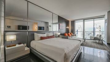 Una habitación de hotel moderna con una cama grande, un escritorio, una silla y un balcón con vista a la ciudad.