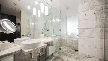 Un baño moderno con dos lavamanos, ducha con cerramiento de vidrio y suelo de mármol.
