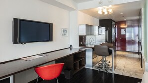 A modern kitchen with stainless steel appliances, a dining area with a red chair, and a TV mounted on the wall. - Strip View Studio • Balcony • No Resort Fee • Free Parking • TE25 (Las Vegas)