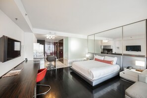 Ein modernes Hotelzimmer mit einem großen Bett, einem Schreibtisch, einem Stuhl, einem Fernseher und einem Spiegel.