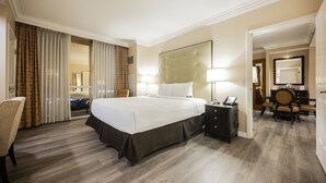 A hotel room with a large bed, a bedside table with a lamp, a chair, and a desk with a chair. - SVS: Remodeled 1BD/2BA | Mountain View Balcony | Full Kitchen | MGM (Las Vegas)