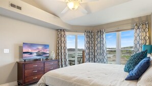 A bedroom with a large bed, a TV on a wooden dresser, and a view of the outdoors through a window. - Family-Friendly, Fishing, & Fun w/ 2 Pools, Views, Boat Slip & Launch (Camdenton)