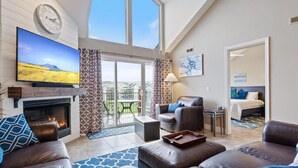 A spacious living room with a fireplace, leather sofas, a flat-screen TV, and a balcony with a view of the countryside. - Family-Friendly, Fishing, & Fun w/ 2 Pools, Views, Boat Slip & Launch (Camdenton)
