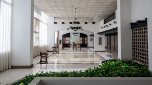 Eine geräumige Lobby mit hoher Decke, einem Kronleuchter und einer Sitzecke mit Stühlen und Tischen.