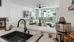Eine moderne Küche mit Spüle, einer Kaffeemaschine und Blick auf den Wohnbereich.