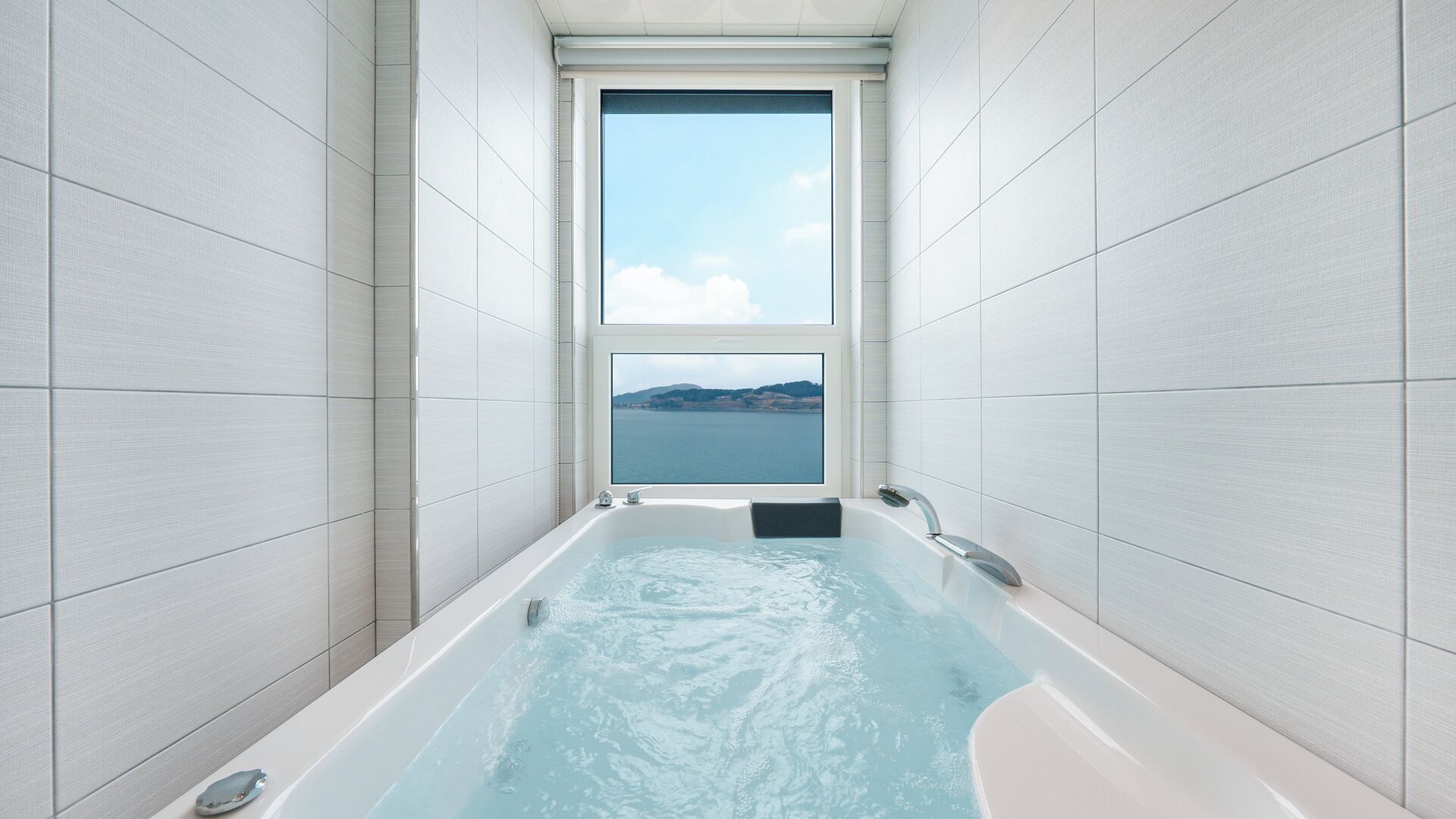 Une salle de bain avec une baignoire, une fenêtre et une vue sur la mer.