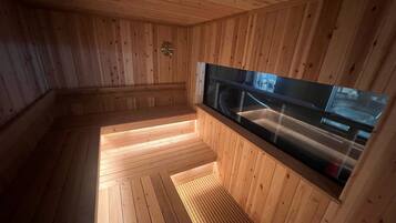 A sauna with wooden walls and a glass window.