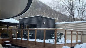 Une terrasse en bois avec une petite cabane, entourée de neige.