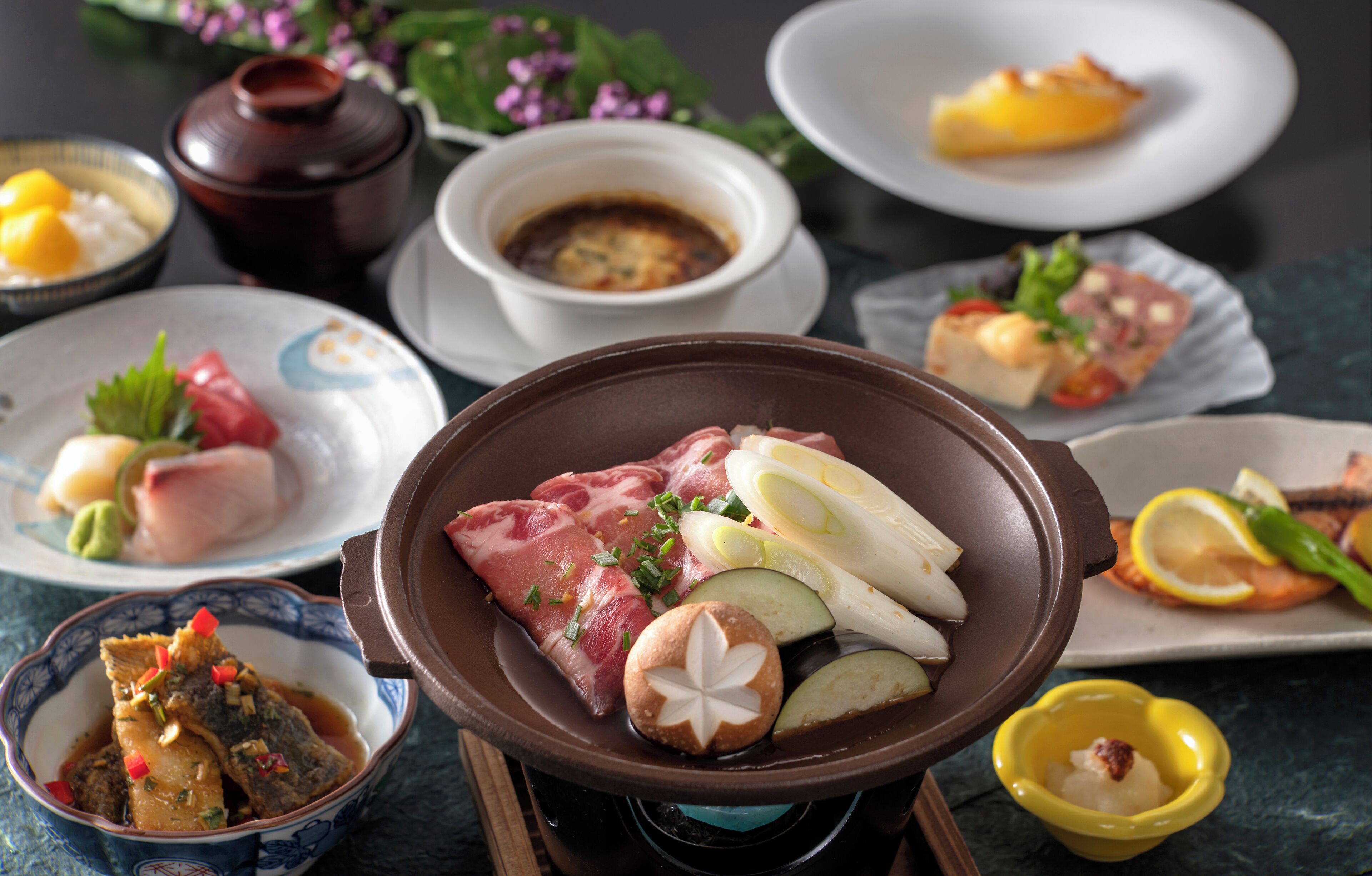A variety of dishes including sashimi, a bowl of soup, and a plate with a slice of cake.