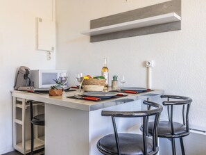 Eine moderne Küche mit einer zentralen Kochinsel, Barhocker, einer Mikrowelle und einem kleinen Topfpflanzen.