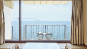 A balcony with a view of the sea, two chairs, and a table. - Shibushiwan Daikoku Resort Hotel (Shibushi)