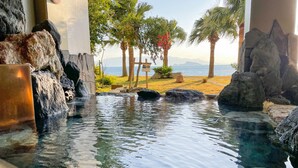 A clear pool with rocks and a view of the beach and mountains. - Shibushiwan Daikoku Resort Hotel (Shibushi)