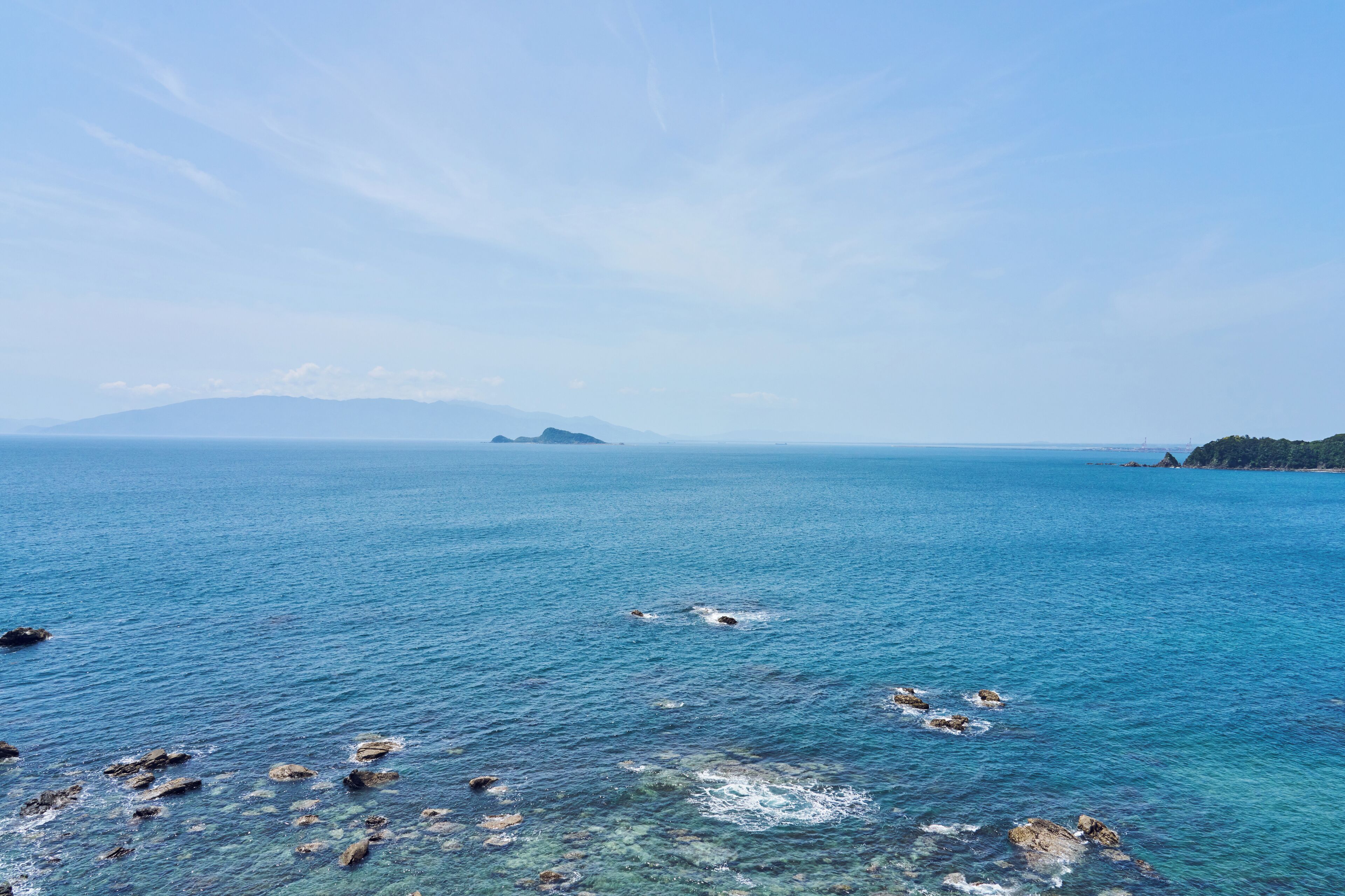 Vista costera con aguas azul turquesa, costa rocosa y islas al lejano.