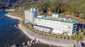 Ein großes Hotel mit mehreren Stockwerken, einem grünen Dach und Blick auf die Küste.