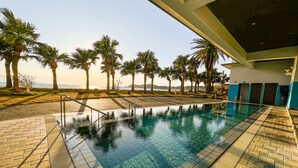 A swimming pool with clear water, surrounded by palm trees and a view of the sea. - Shibushiwan Daikoku Resort Hotel (Shibushi)