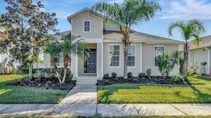 A two-story house with a front porch, a small garden with palm trees, and a clear sky. - Spacious 4-bedroom villa in nice Kissimmee Florida (Kissimmee)
