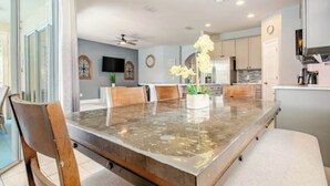 A modern kitchen with a large island, wooden chairs, and a dining table. - Spacious 4-bedroom villa in nice Kissimmee Florida (Kissimmee)
