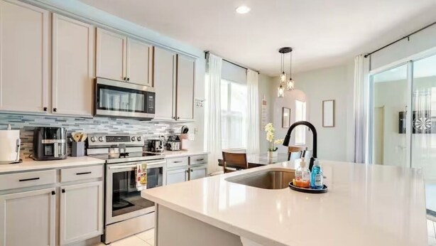A modern kitchen with white cabinets, stainless steel appliances, and a large island with a sink. - Spacious 4-bedroom villa in nice Kissimmee Florida (Kissimmee)