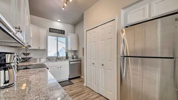 A modern kitchen with white cabinetry, a stainless steel refrigerator, and a granite countertop. - Wyngate Retreat Mtn view home, BBQ, 4 bed, 17 Mi from Snowbird. (South Jordan)