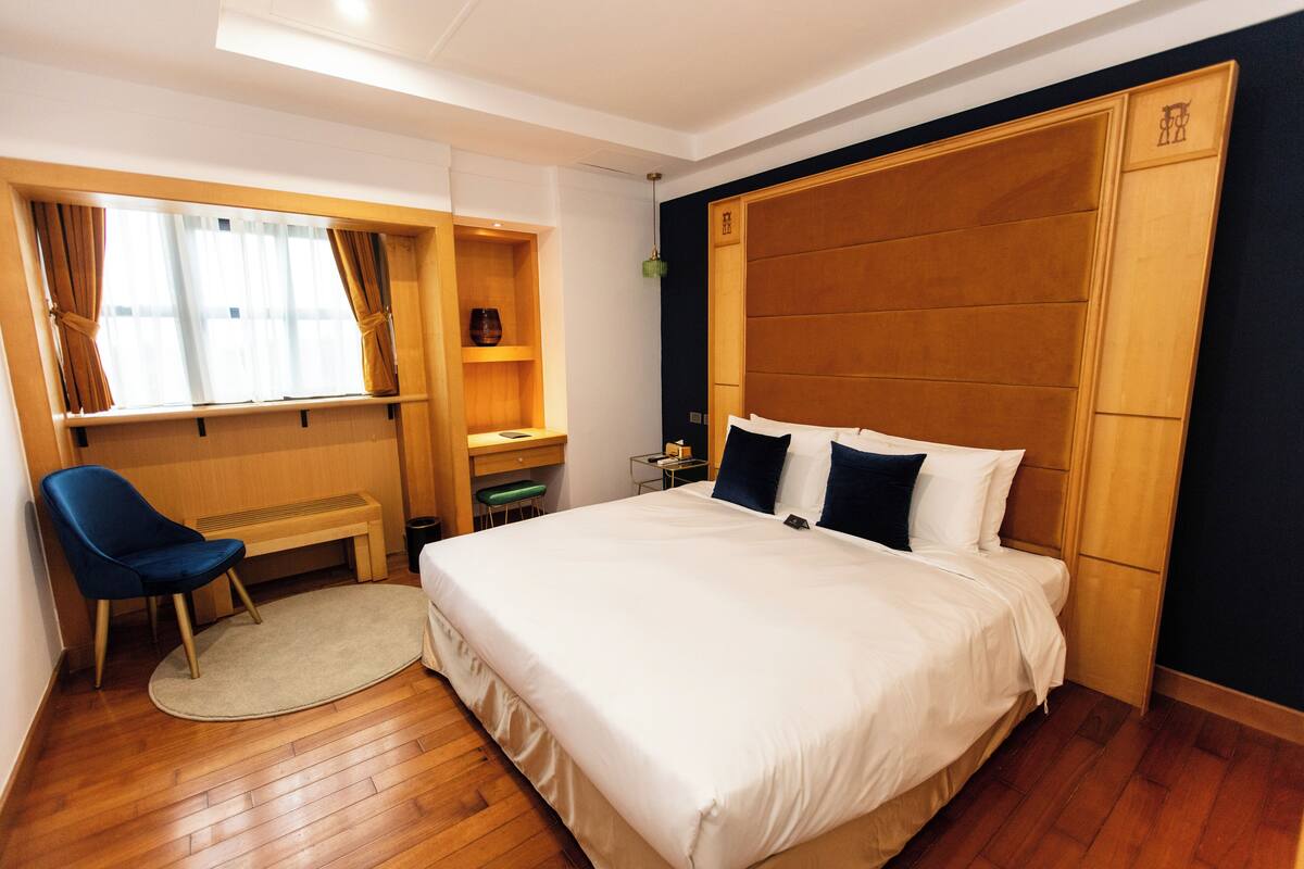 A hotel room with a large bed, a desk, and a chair.