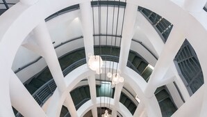Een meerlaags interieur met een centrale spiraaltrap, witte structurele elementen en hangende, bolvormige lampen.