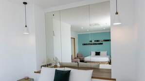 Een moderne hotelkamer met een grote spiegel, een bed met witte lakens, een nachtkastje en een groene vaas.