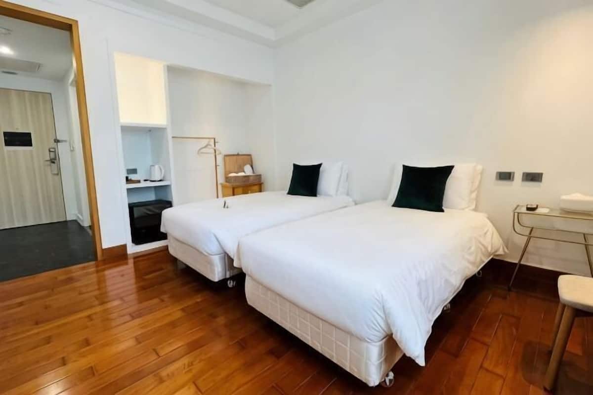 A hotel room with two beds, a desk, and a chair.