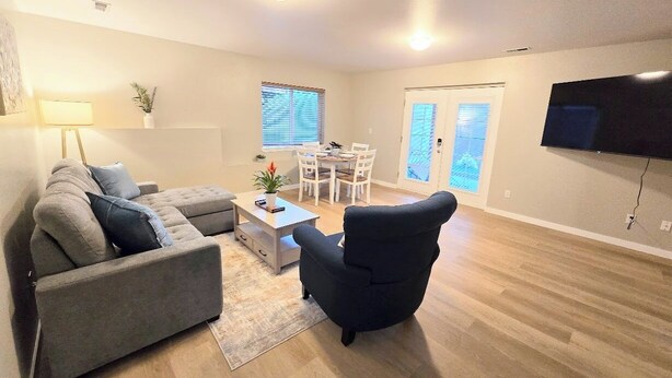 A modern living room with a grey sectional sofa, a black armchair, a coffee table, and a flat-screen TV mounted on the wall. - 2 bed 2bath guest house with private entrance, near light rail & Seattle (Lynnwood)