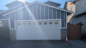 A residential garage with a white door, a brick foundation, and a wooden fence. - 2 bed 2bath guest house with private entrance, near light rail & Seattle (Lynnwood)