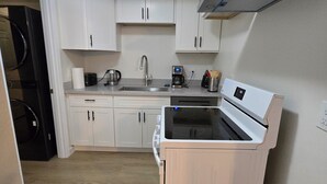 A compact kitchen with white cabinets, a stainless steel sink, a coffee maker, and a built-in oven. - 2 bed 2bath guest house with private entrance, near light rail & Seattle (Lynnwood)
