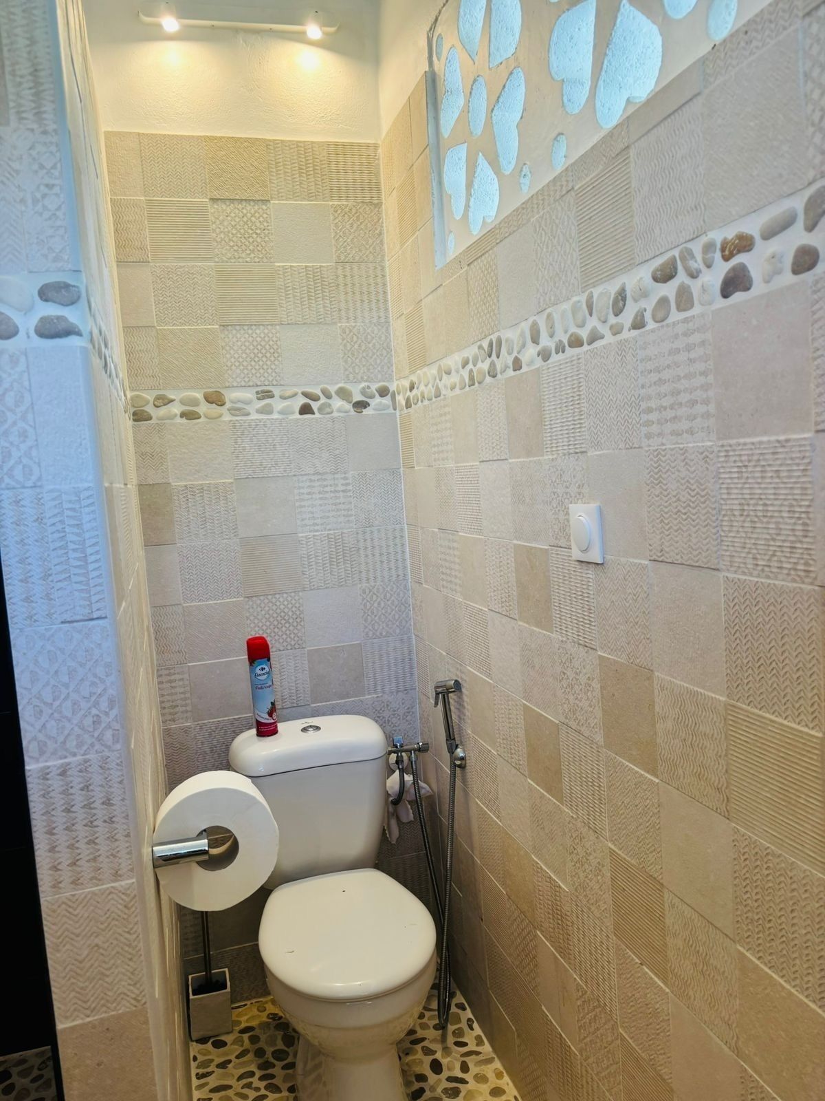 A small bathroom with a toilet, a shower, and a patterned wall.