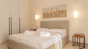 A modern hotel room with a large bed, two bedside tables, a wardrobe, and a painting on the wall. - Homiday- House L -Wood beams and comfort by the sea (Livorno)