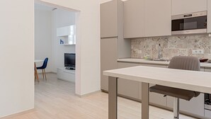A modern kitchen with a microwave, oven, and a dining area with a table and chairs. - Homiday- House L -Wood beams and comfort by the sea (Livorno)
