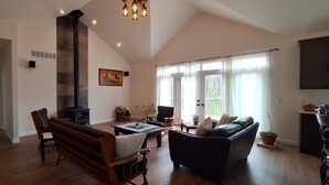 Un salón comedor espacioso con techo alto, chimenea y amplios ventanales.
