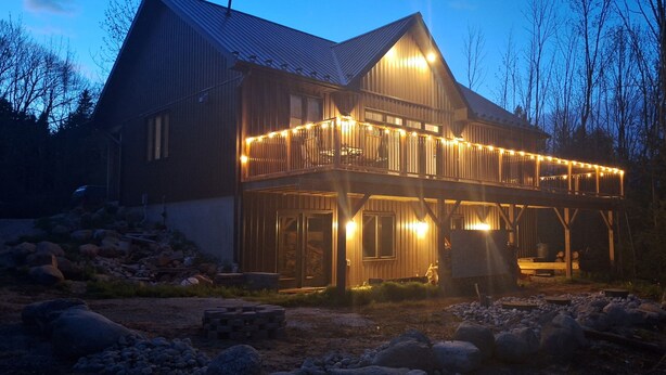 Una casa de madera grande con balcón, rodeada de rocas y árboles.