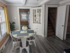 A dining area with a round table, white chairs, and a vase of flowers.