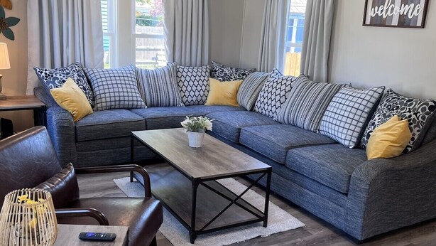 A modern living room with a sectional sofa, a coffee table, and a TV stand.
