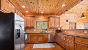 A kitchen with wooden cabinets, a stainless steel refrigerator, and a wooden ceiling.