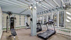 Een sportschool met loopbanden, een hometrainer en een roeiapparaat.