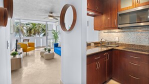 A modern kitchen with wooden cabinets, a stainless steel microwave, and a tiled backsplash.