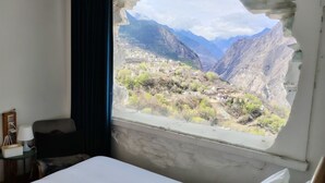 A hotel room with a large window offering a view of a mountainous landscape. - LaMaiSon (Garze)