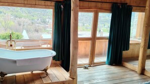 A room with a freestanding bathtub, wooden flooring, and large windows with curtains. - LaMaiSon (Garze)