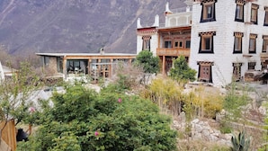 A traditional building with a balcony and a view of a mountainous landscape. - LaMaiSon (Garze)