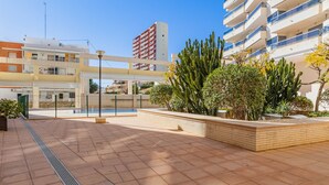 Une cour avec une piscine, entourée de bâtiments et de cactus.