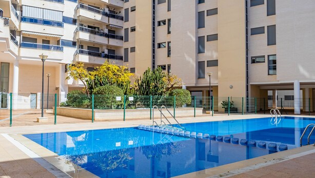 Un immeuble d’appartements moderne doté d’une piscine, de balcons et surplombant un ciel d’un bleu éclatant.