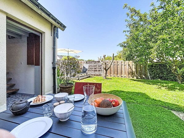 A patio with a table set for a meal, a potted plant, and a wooden fence in the background.